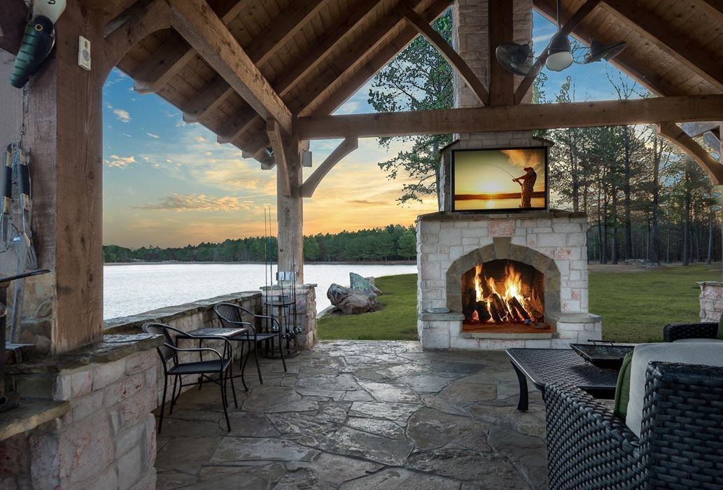 Covered patio with a stone fireplace looking toward water and trees, Carroll Creek Ranch, Red River County, Texas