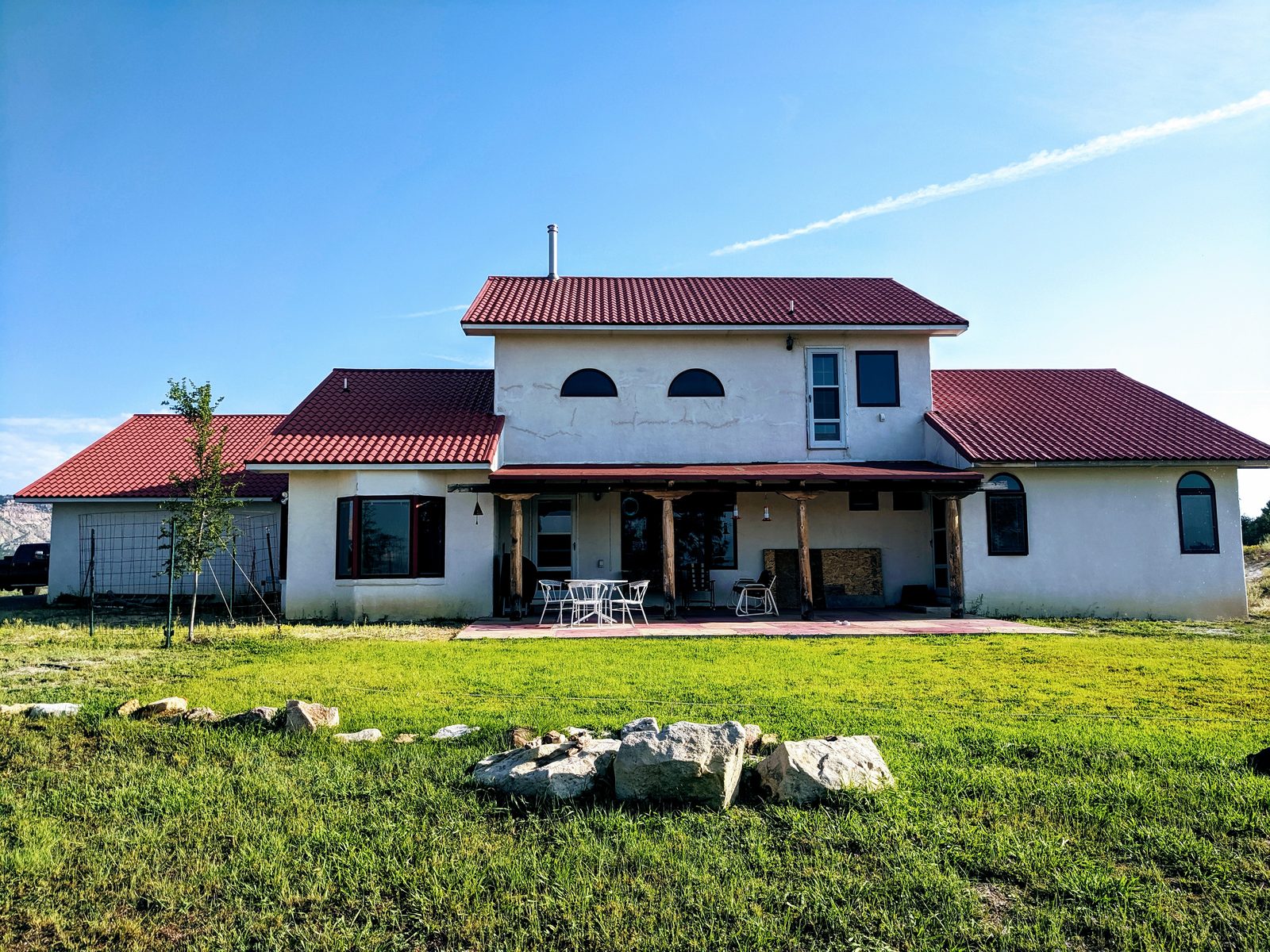 White stucco house with red tile roof, covered patio, and lawn at Casa Blanca, Rio Arriba County, New Mexico