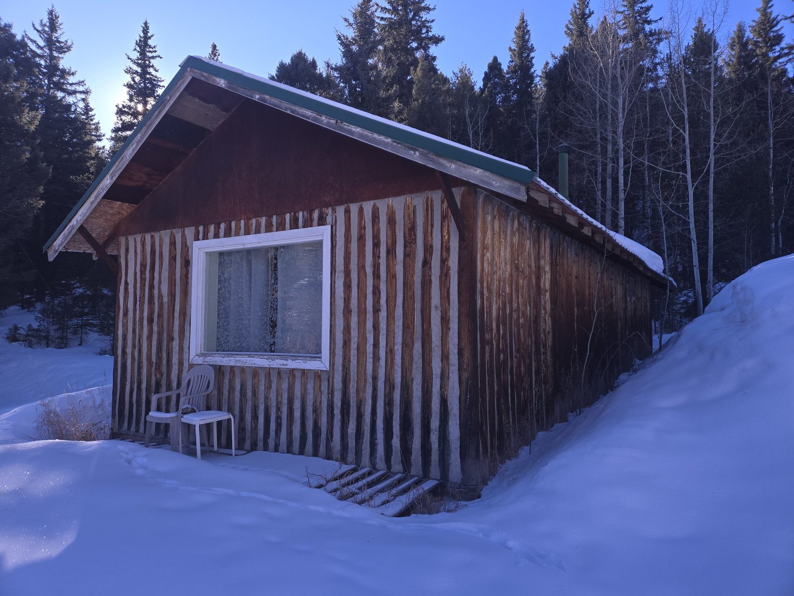 Rustic wood cabin in the snow among pines and aspens at Foxton Retreat, Jefferson County, Colorado