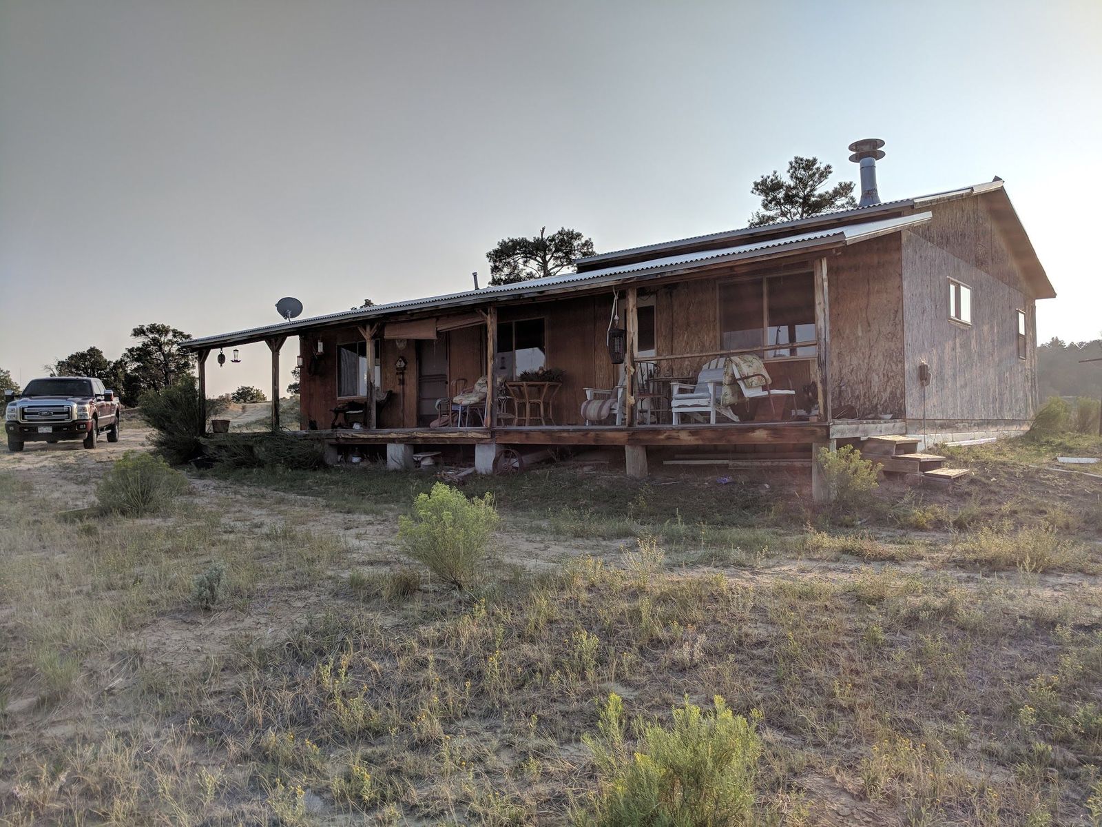 Wood house with a covered porch and a parked pickup at Gloria a Dios, Rio Arriba County, New Mexico