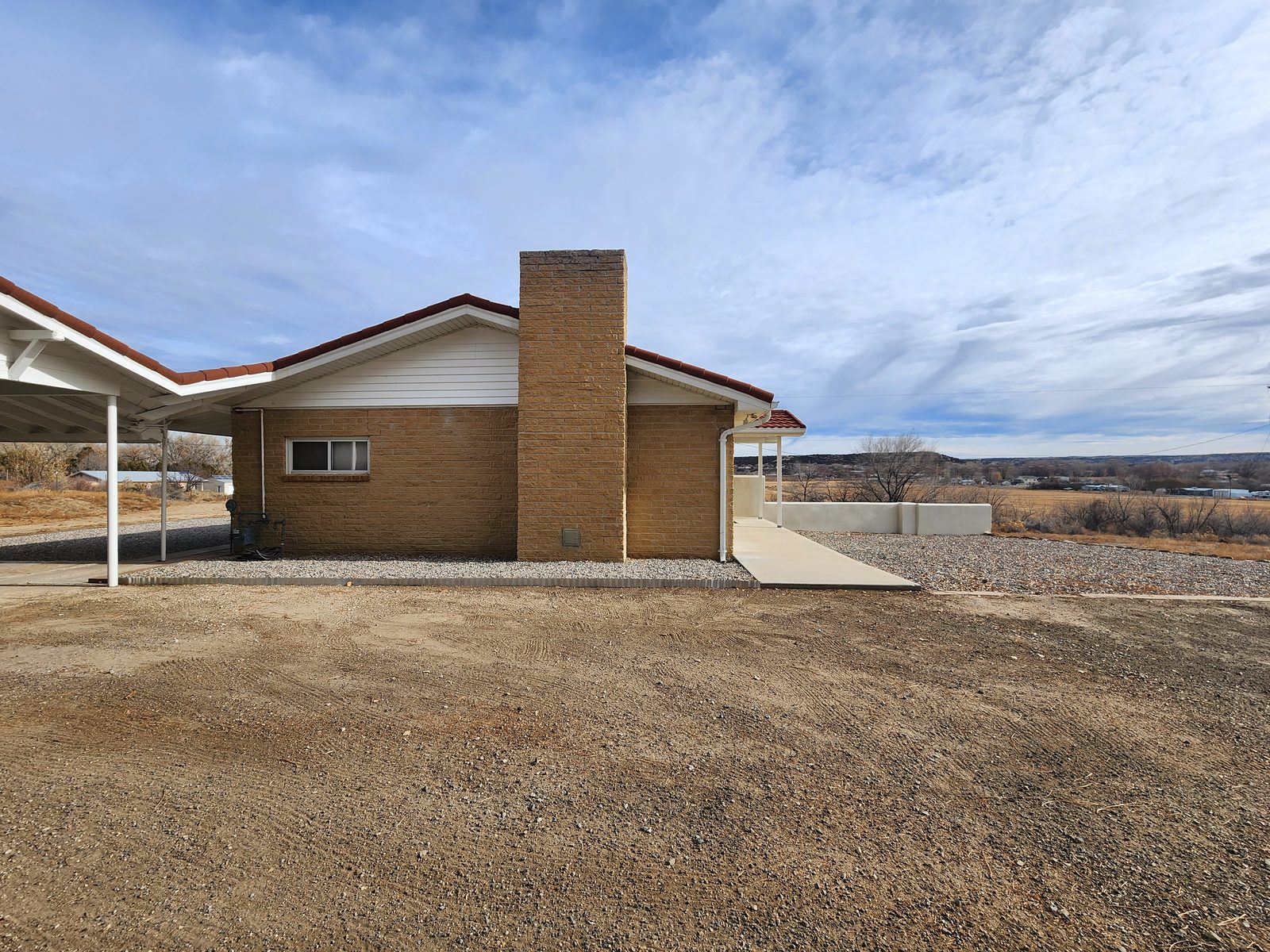 Brick ranch house with a carport and gravel yard at Gomez Farm, San Juan County, New Mexico
