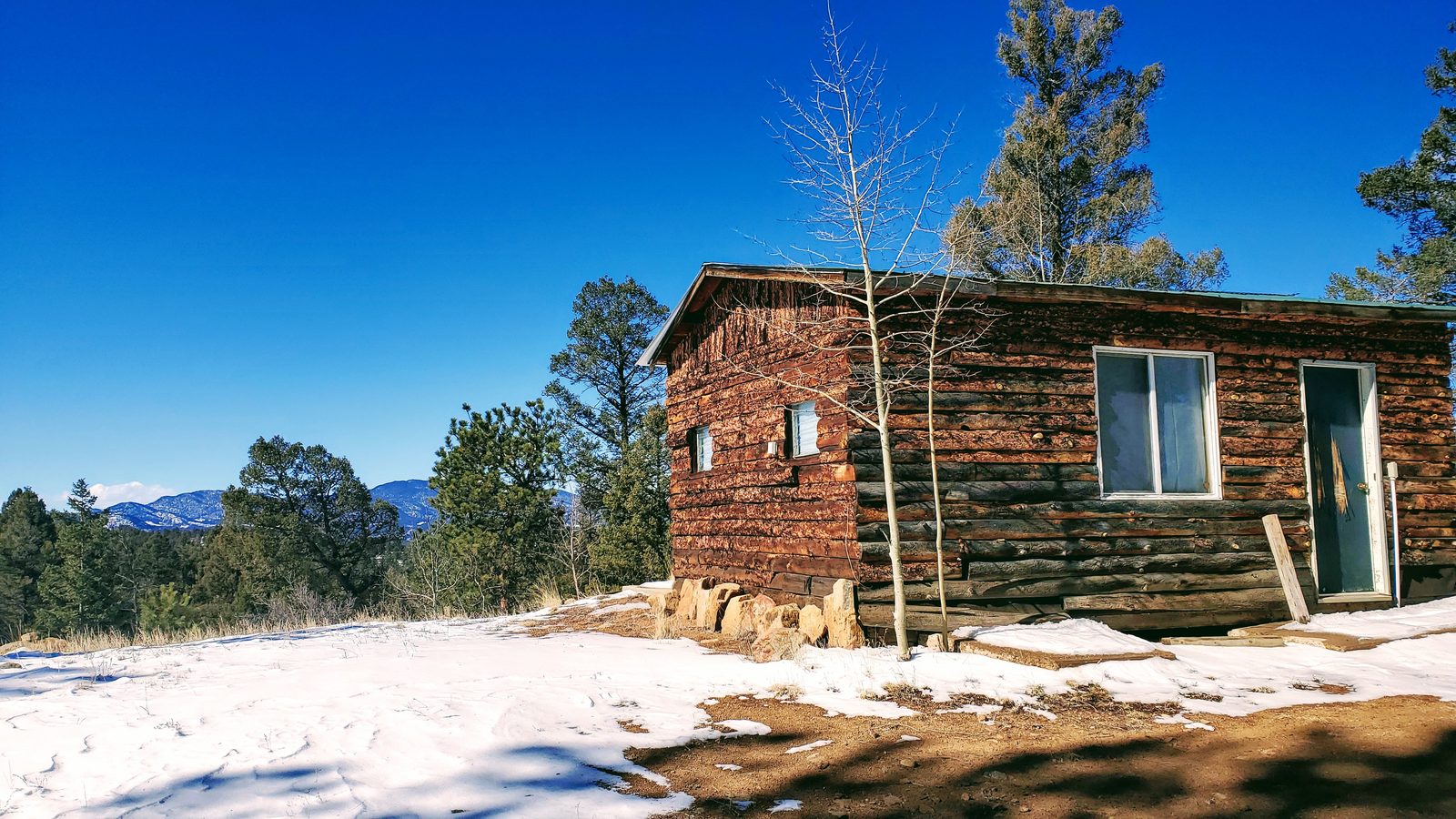 Rustic log-sided cabin on a rise with mountain views at Horse Creek Ranch, Lake George, Teller County, Colorado
