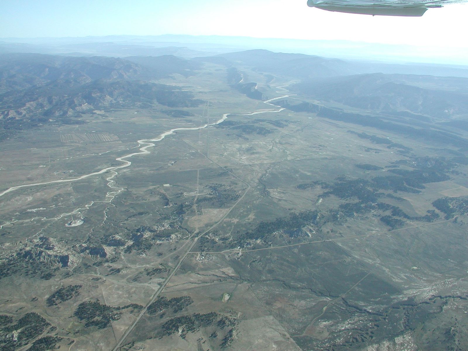 Aerial view of a winding valley, roads, and distant mountains, Little Arroyo Blanco, Rio Arriba County, New Mexico