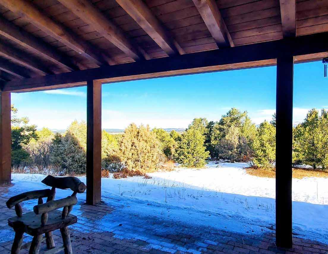 Covered porch looking over snow and pines at Los Piñones Ranch, Rio Arriba County, New Mexico