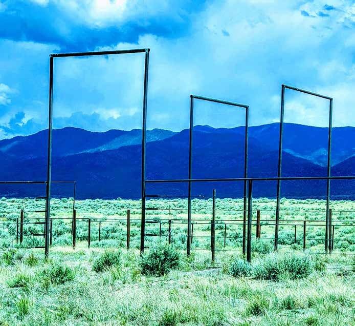 Metal fence and gate in sagebrush pasture with mountains at Taos Enchanted Valley, Taos County, New Mexico