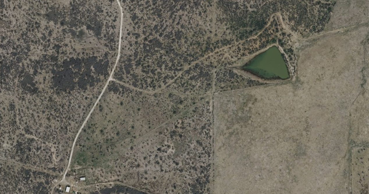 Aerial view of brush pasture, ranch roads, and a stock tank at Wallace Creek Ranch, San Saba County, Texas